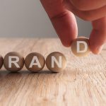 Hand putting on brand word written in wooden cube